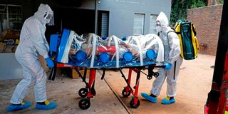 Paramedics use an isolation chamber to push a man showing Covid-19 symptoms 