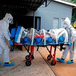 Paramedics use an isolation chamber to push a man showing Covid-19 symptoms 