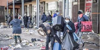 Looters take away items left in a vandalised mall in Vosloorus