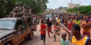 People celebrate in the streets with members of Guinea's armed forces.