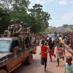People celebrate in the streets with members of Guinea's armed forces.