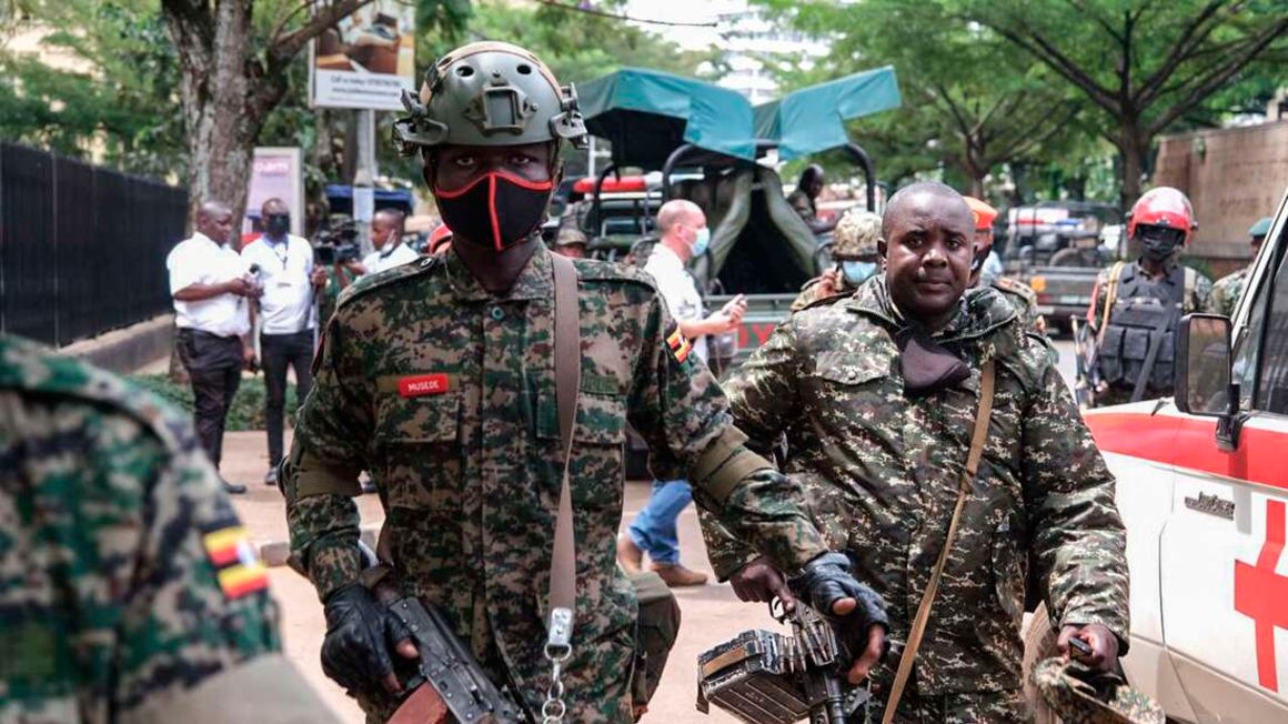 Members of Uganda People's Defence Force (UPDF) walk near a bomb explosion site in Kampala.