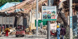 Residents walk past a bomb explosion site in Mogadishu, Somalia.