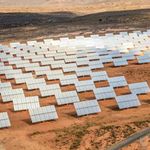 Rows of solar panels in arid landscape.