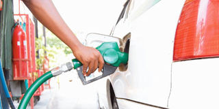 A petrol station attendant fuels a car.