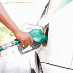 A petrol station attendant fuels a car.