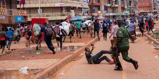 A police officer chases street vendors in Kampala, Uganda 