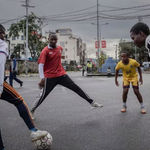 Young people play football on a street in Goma, DRC