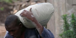 A man carrying a bag of cement.