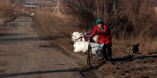 An elderly woman pushes her bicycle in Ukraine’s Kharkiv