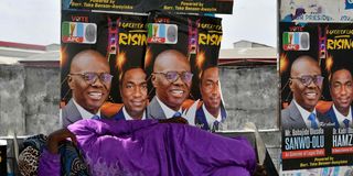 A woman lies beside campaign posters in Lagos