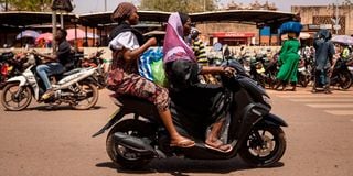 A woman rides a motorcycle in Ouagadougou, Burkina Faso