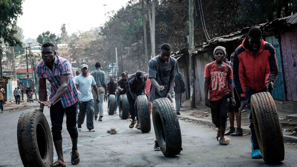 Protesters roll tyres towards a barricade in Kibera, Nairobi