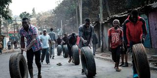 Protesters roll tyres towards a barricade in Kibera, Nairobi