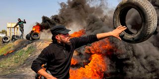A Palestinian man adds tires to a fire