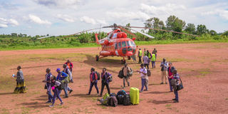 Aid workers and passengers disembark from a UNHAS helicopter