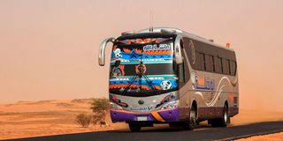 A passenger bus drives along a desert road in al-Gabolab, Sudan