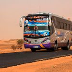 A passenger bus drives along a desert road in al-Gabolab, Sudan