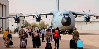 People prepare to board a UK military plane to evacuate from Sudan