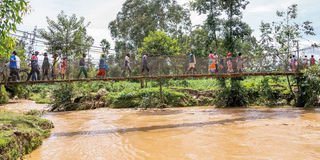 Rwanda floods - People walk over a water bridge 