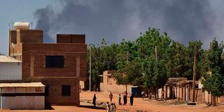 People walk as smoke billows in Khartoum, Sudan