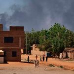 People walk as smoke billows in Khartoum, Sudan