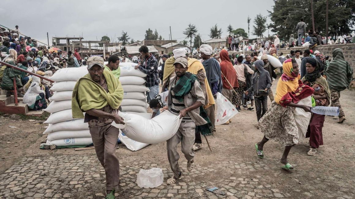 Men carry a sack of wheat during food distribution by WFP 