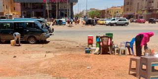 a woman sells drinks in a street in southern Khartoum