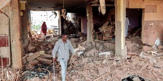 People walk through the rubble as they inspect a house that was hit by an artillery shell 