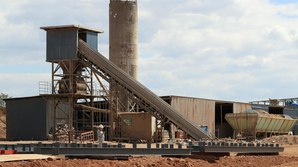 A worker checks their mobile phone as Zimbabwe's President Emmerson Mnangagwa commissions the Prospect Lithium mine 